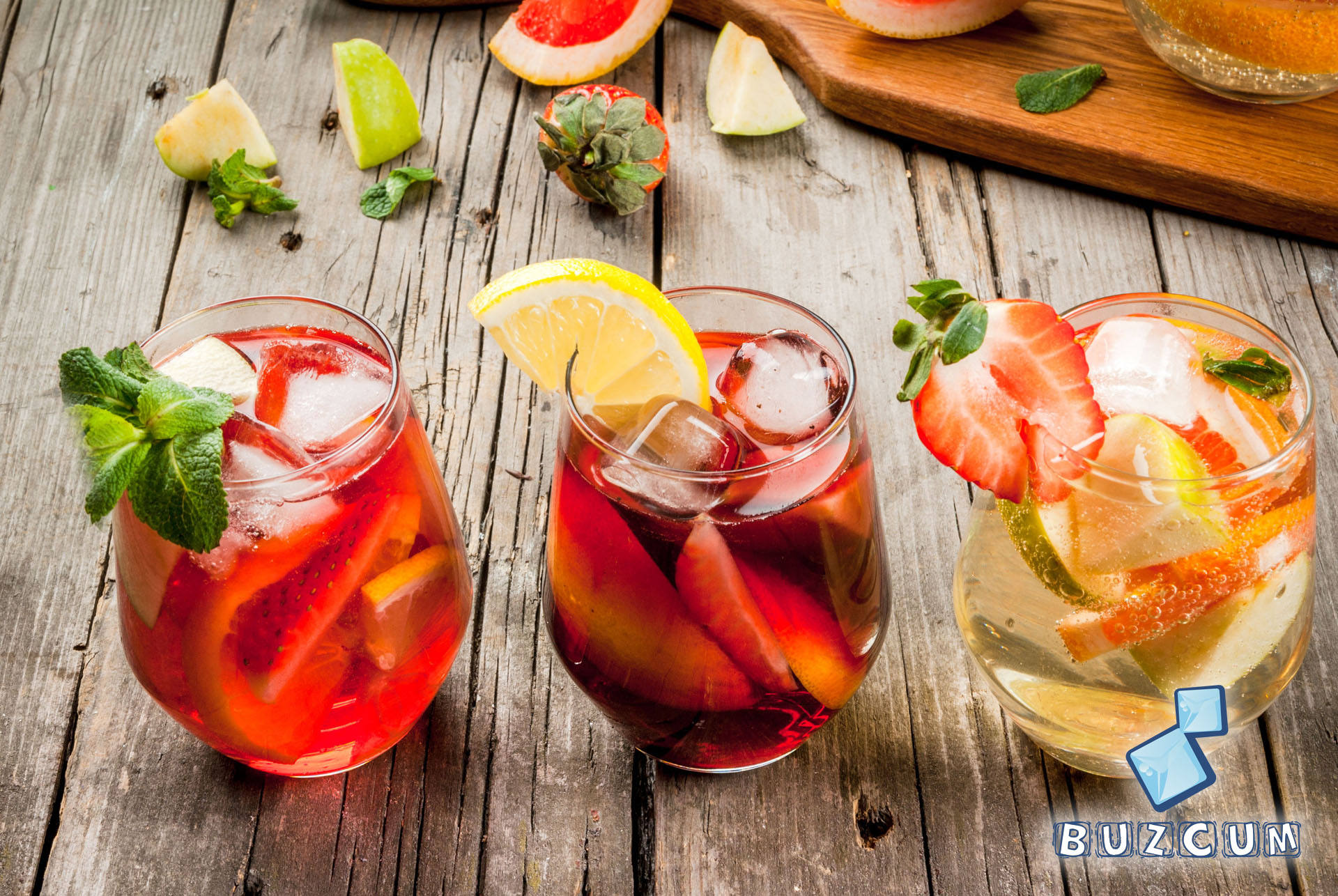 Traditional summer drink sangria - red, pink and white. With champagne, pink and red wine, strawberries, oranges, lemon, green apple and grapefruit. On a wooden rustic table, copy space